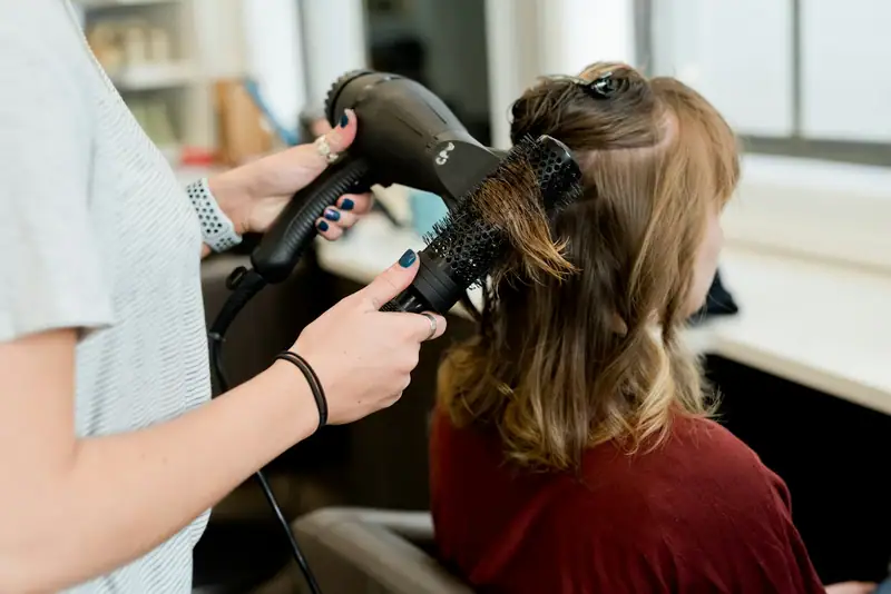 Stylist blow-drying hair with a round brush