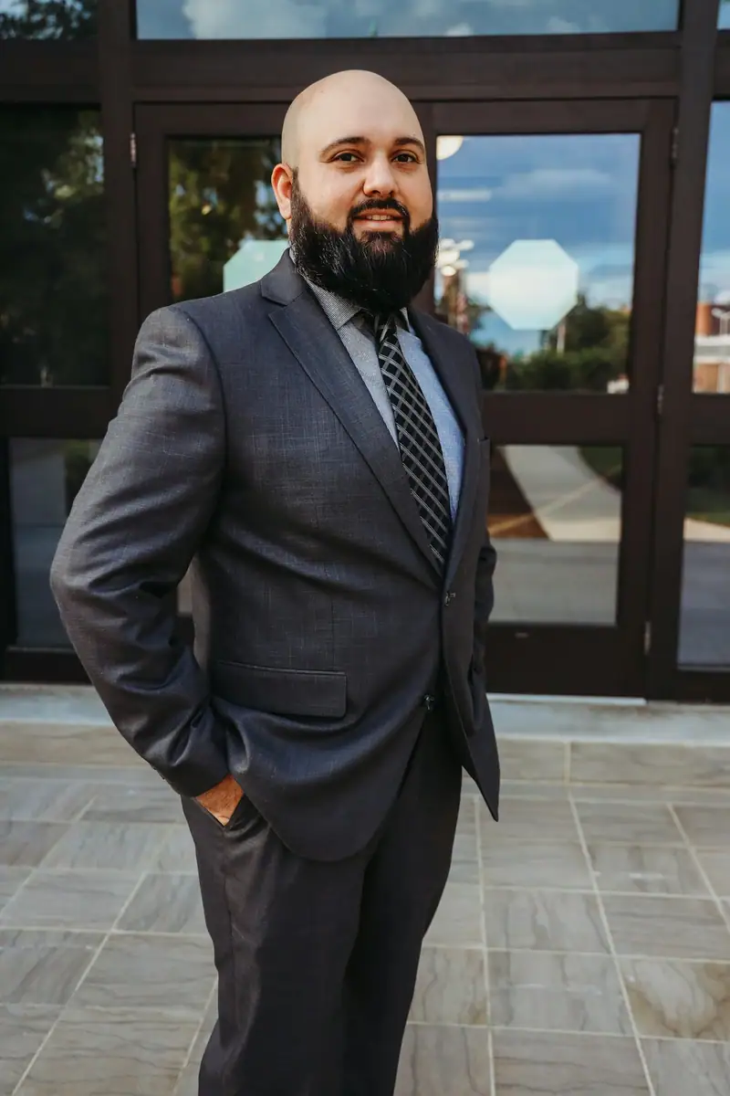 Bearded man in a grey suit standing in a doorway