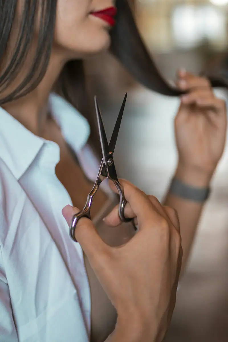 Hand holding scissors and a lock of hair