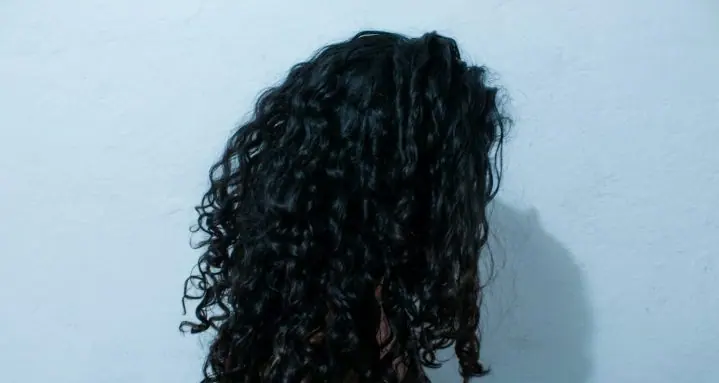 Dark curls, pale blue wall