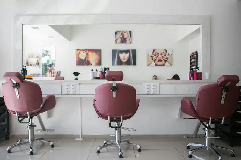 Salon interior with three maroon chairs facing a mirror wall