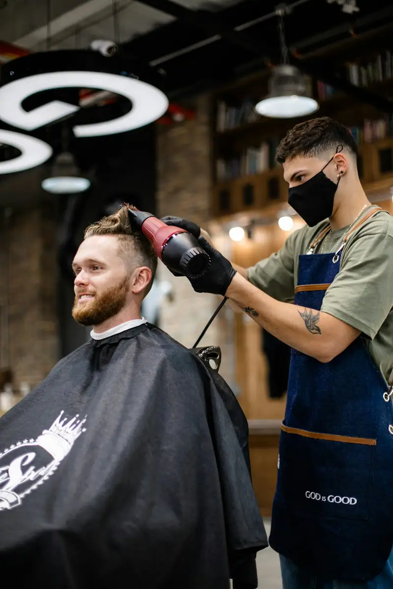 Barber blow-drying a bearded client's hair
