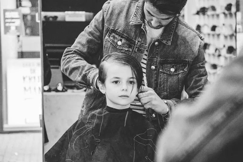 Black and white photo of a boy in a barber chair
