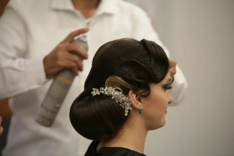 Stylist finishing a sculpted updo with spray