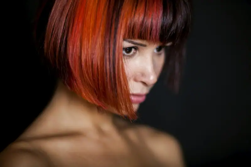 Copper-red bob with a sharp fringe against a dark background