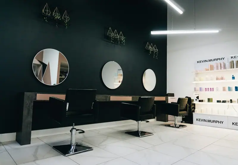 Dark salon with round mirrors and black styling chairs