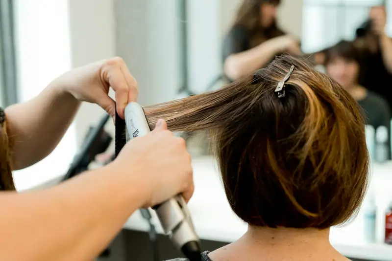Stylist smoothing a bob with a flat iron